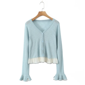 Close-up of light blue cardigan featuring white ruffle trim hem and buttoned V-neck