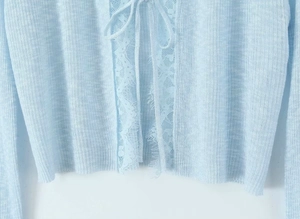 Detail of light blue knit cardigan with delicate eyelash lace trim and tie closure front
