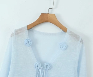 Detail of light blue sheer knit cardigan with 3D crochet flower appliqués and tie closure