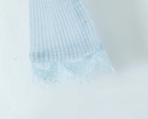 Close-up of light blue ribbed knit fabric with delicate eyelash lace trim detail