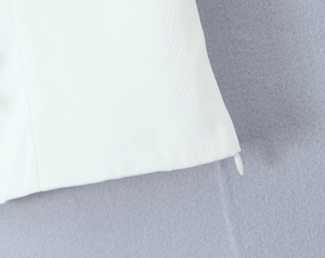 Close-up of invisible zipper detail on white woven bow top with premium stitching
