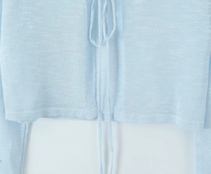 Detail of light blue lightweight knit cardigan with delicate ties and soft texture