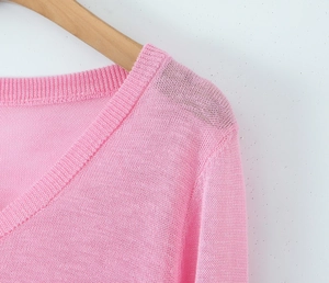 Detail of V-neck pink cardigan showing ruffled lettuce edges and fine knit texture