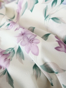 Detailed macro view of lightweight chiffon fabric with delicate purple floral print patterns