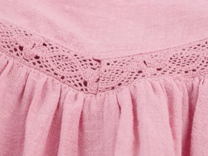Detail of pink cotton fabric with intricate white lace crochet and pleated texture