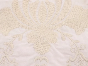 Gros plan de broderies florales complexes sur tissu en popeline de coton blanc cassé