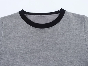 Close-up of the grey knit top featuring a contrasting black ribbed crew neckline