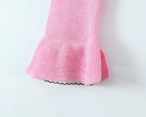 Close-up of ruffled cuff detail on pink knitted cardigan with fine needlework texture