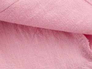 Detailed macro view of pink textured cotton fabric and refined stitching on the sleeve