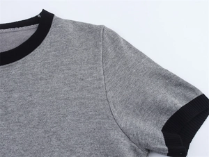 Detail of grey knitted short sleeve top with black ribbed neckline and sleeve cuffs