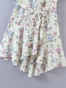 Close-up of floral summer dress featuring ruffled hem and matching bow tie waist detail