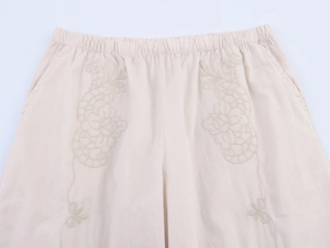 Détail de la taille élastique d'un short crème avec broderie florale et poches latérales