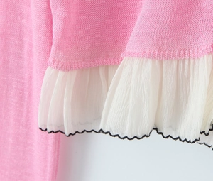 Detail of pink knit fabric featuring white ruffle hem with delicate black edge stitching