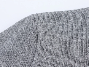 Close-up of contrast stitching and high-density knit fabric on the gray sweater shoulder