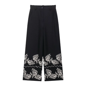 Détail de broderie florale bohème sur pantalon large taille haute en mélange de lin noir