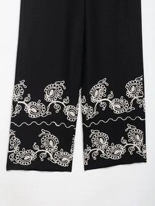 Gros plan sur la broderie florale blanche d'un pantalon large noir en mélange de lin chic