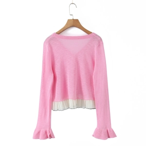 Detail of pink long-sleeve knit cardigan with ruffled cuffs and white chiffon hem