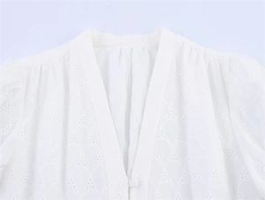 Close-up of white V-neck dress featuring delicate Broderie Anglaise hollow embroidery details