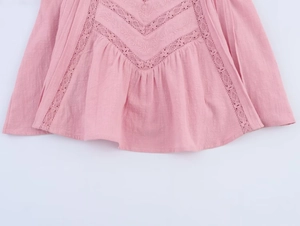 Detailed macro view of light pink cotton top with floral embroidery and lace trim