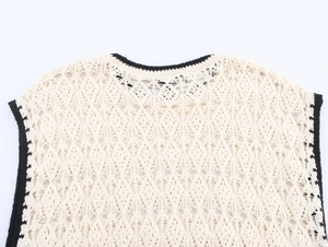 Dettaglio ravvicinato del gilet in maglia crochet bianco con bordi neri e motivi a rombi