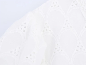 Close-up of white dress showing intricate eyelet embroidery and wavy geometric textures