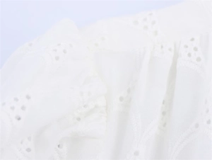 Detailed close-up of white eyelet lace fabric with intricate embroidery for summer dresses