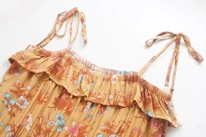 Detail of floral printed summer dress with adjustable tassel straps and ruffled neckline