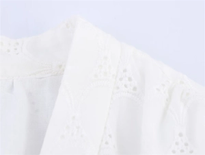 Detailed close-up of white dress with intricate eyelet embroidery and hollowed-out patterns