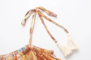 Close-up of bohemian floral print dress with adjustable tie straps and ivory tassels