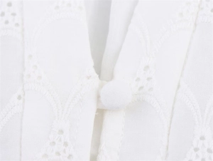 Macro detail of French V-neck dress featuring delicate embroidery and fabric-covered buttons