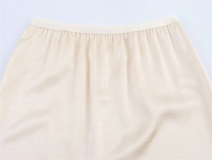 Close-up of pleated ivory satin skirt waist showing high-quality stitching detail