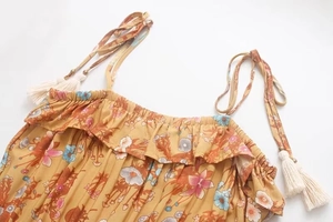Detail of bohemian floral print dress with ruffle neckline and tassel drawstring ties