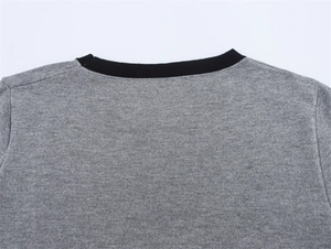 Detail of grey knit sweater showing black ribbed crew neckline and high-quality fabric texture
