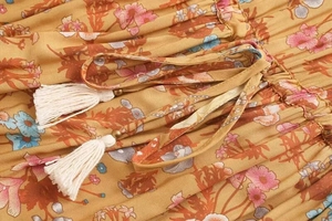 Detailed shot of bohemian floral dress with drawstring waist and white tassel charms