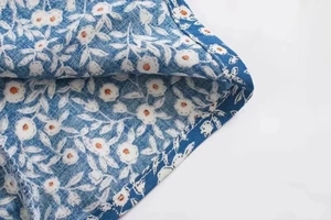 Detail von bedrucktem Viskosestoff auf marineblauem Kleid mit sichtbaren Nähten und Textur