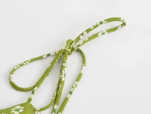 Detail of green floral dress featuring white daisy print and delicate shoulder straps