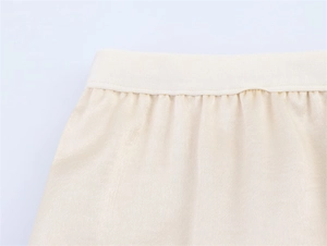 Close-up of the ribbed elastic waistband and soft fabric texture on a cream midi skirt