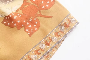 Detail of bohemian floral print on ginger yellow fabric with delicate hem stitching