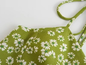 Macro shot of green daisy print dress fabric and delicate spaghetti strap details