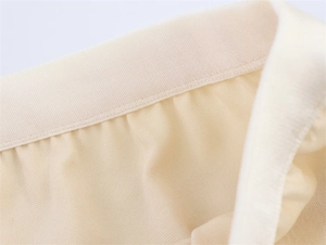 Detailed close-up of beige knit fabric texture and elastic waistband with fine stitching