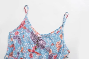 Détail des bretelles réglables et boutons en bois sur une robe d'été à fleurs
