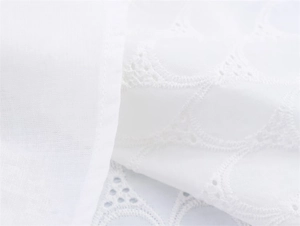 Close-up of white Broderie Anglaise fabric with intricate embroidery and cutout details