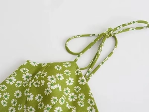 Detail of green floral dress featuring white daisy print and delicate spaghetti straps