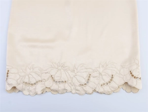 Detailed embroidery and eyelet cutouts on champagne silk skirt with scalloped hemline