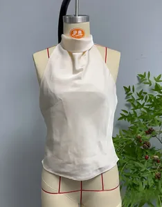 Dettaglio del top a lupetto in raso bianco con elegante trama dello scollo a pieghe
