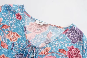 Detail of V-neckline on floral print blue shirt with tie string and white button