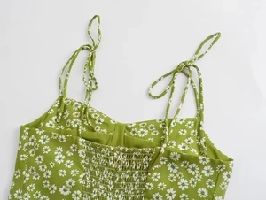 Detail of green floral dress featuring adjustable tie straps and smocked elastic back part