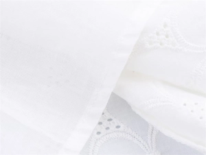 Close-up of white dress showing intricate eyelet embroidery and hollow knit cotton texture