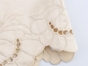 Close-up of beige scalloped edge skirt with intricate floral eyelet embroidery detail