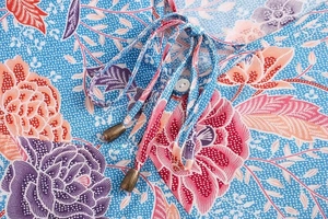Close-up of V-neck tie detail on sky blue Bohemian floral long sleeve shirt fabric